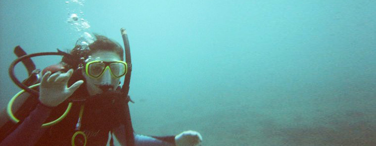 Jessica scuba diving and waving under Hawaiian waters.